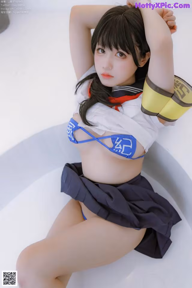 A woman in a blue and white outfit sitting in a bathtub.