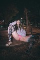 A woman sitting on a bench in a park at night.