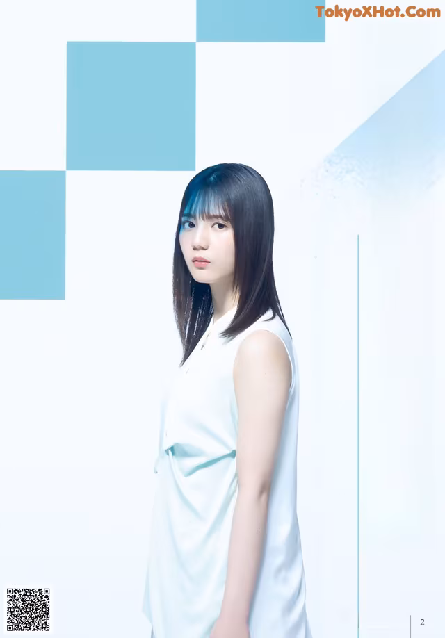 A woman in a white dress standing in front of a blue and white background.