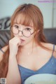 A woman wearing glasses eating a bowl of food.