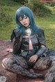 A woman with blue hair sitting on a blanket.