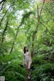 A woman in a bathing suit walking through a forest.