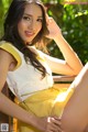 A woman in a yellow dress sitting on a wooden bench.