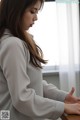 A woman leaning against a window looking out the window.