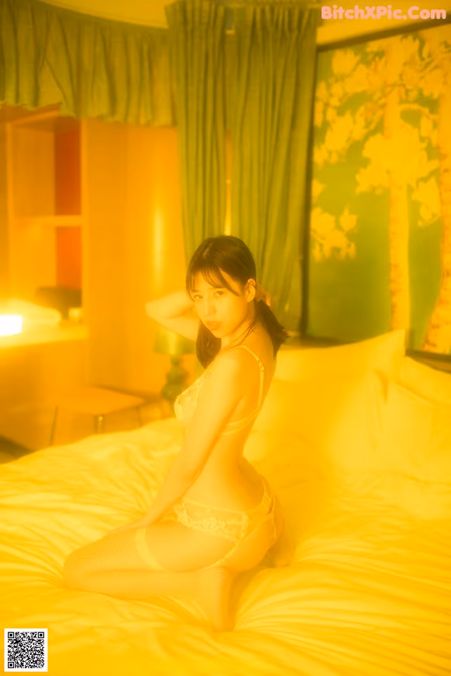 A woman sitting on a bed in a white lingerie.