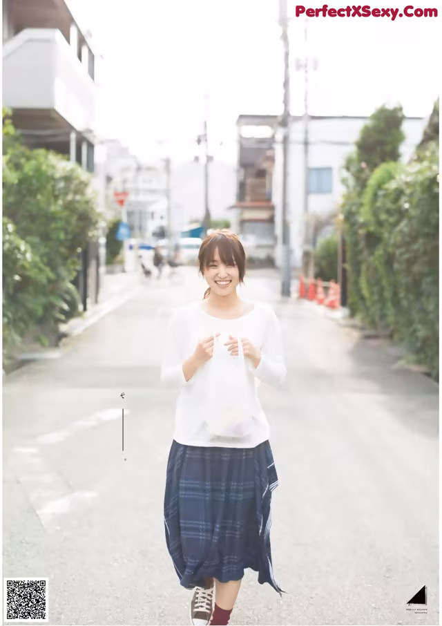 A woman walking down a street holding a bag.