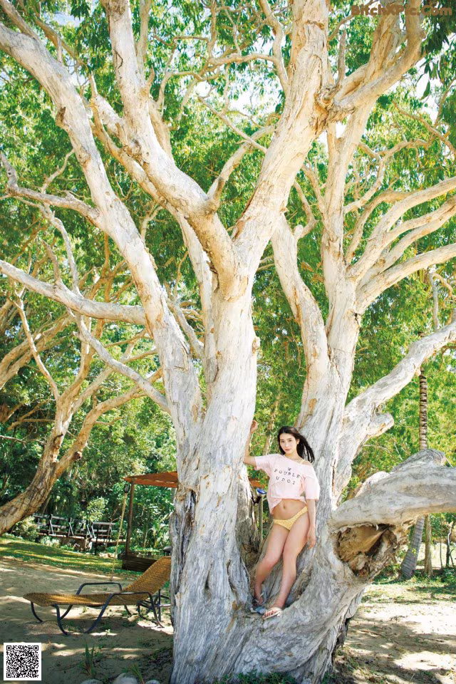 A woman leaning against a tree in a park.