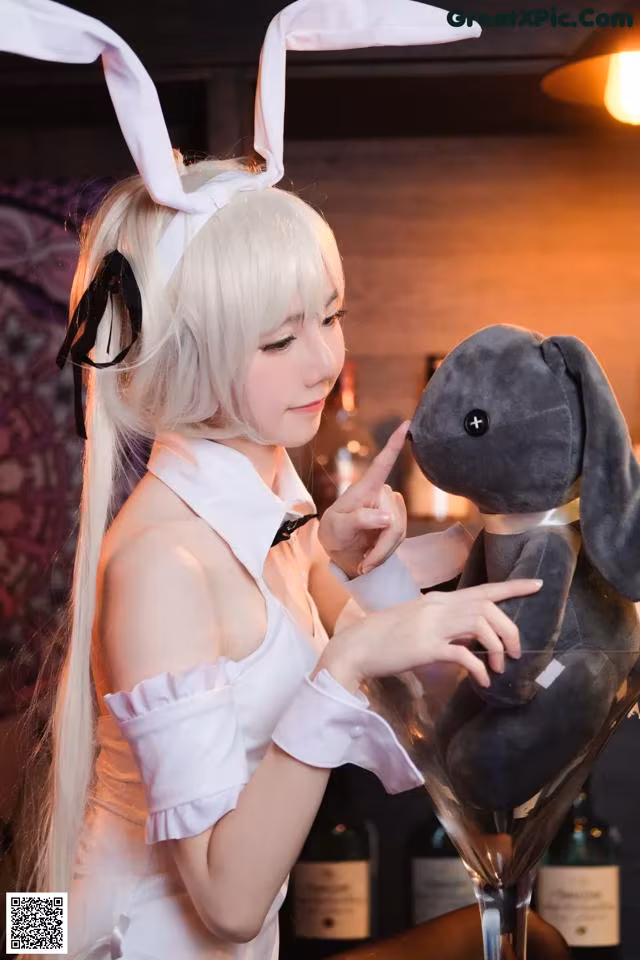A woman in a bunny costume holding a stuffed animal.