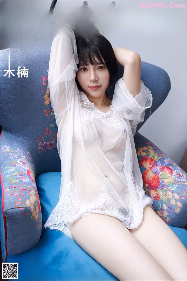 A woman in a white lingerie sitting on a blue chair.