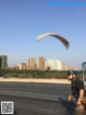 A man is paragliding on the side of the road.