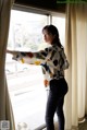 A woman standing in front of a window with her arms outstretched.