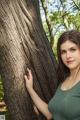 A woman leaning against a tree in the woods.