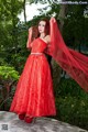 A woman in a red dress standing on a rock.