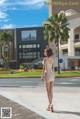 A woman in a beige dress is walking down the street.