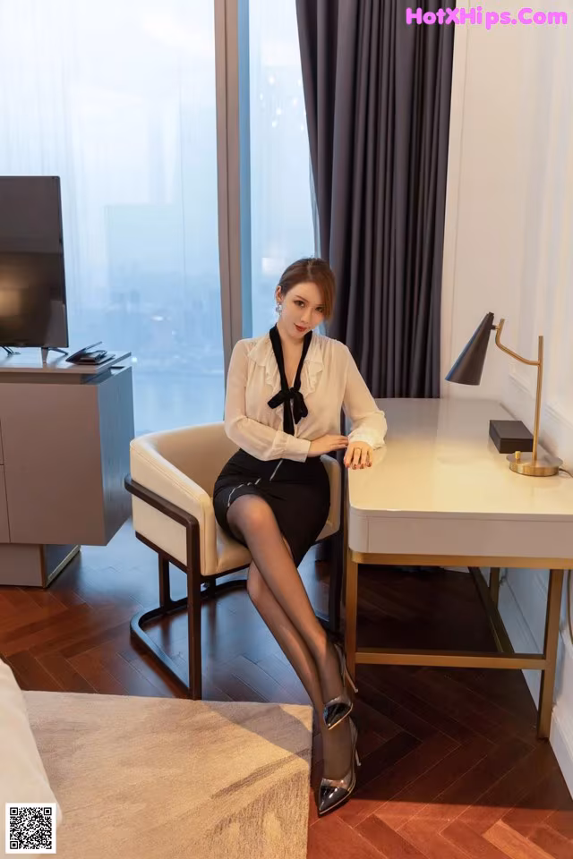 A woman sitting at a desk in a hotel room.