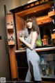 A woman standing in front of a refrigerator holding a glass of wine.