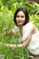 A woman in a white dress sitting in the grass.