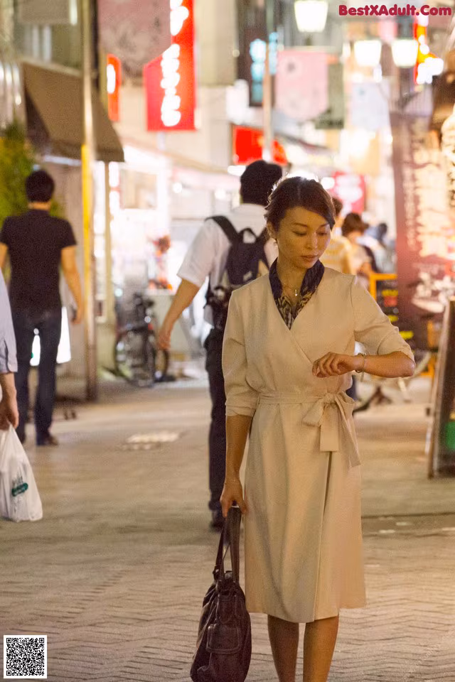 A woman walking down a city street at night.