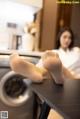 A woman sitting on top of a table next to a washing machine.