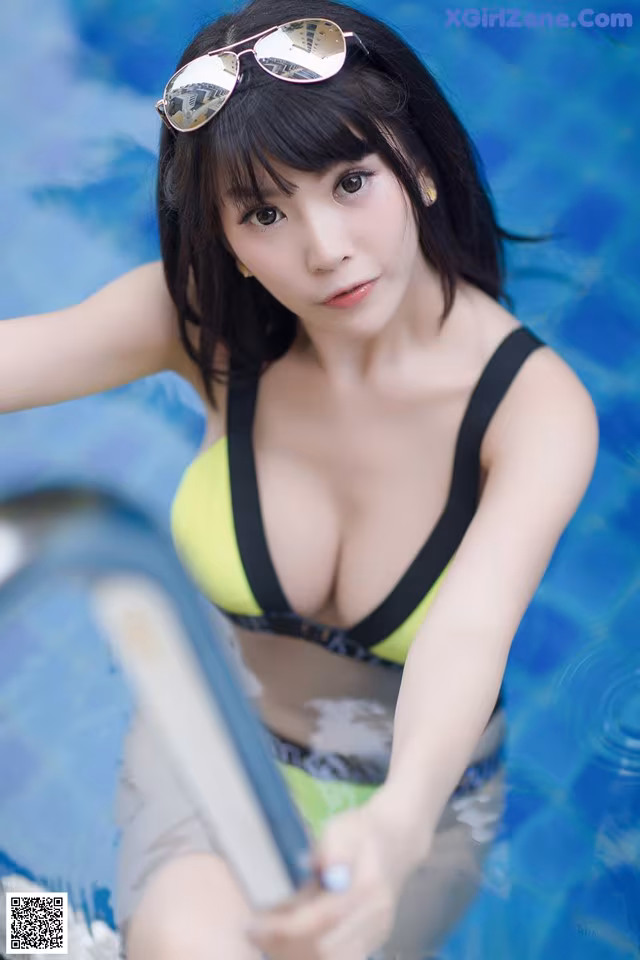 A woman in a yellow bikini sitting in a pool.
