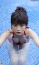 A woman in a red bikini sitting in a pool.