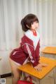 A woman in a school uniform sitting at a desk.